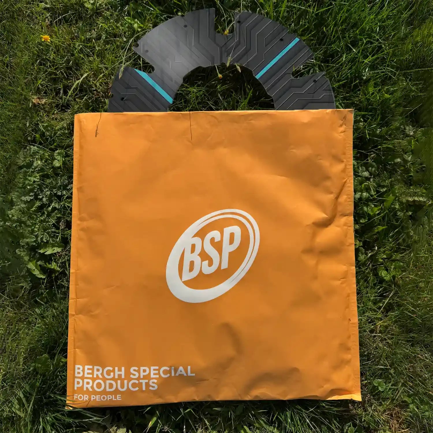 Printed wheelchair spoke guard with modern design on grass, next to orange BSP bag