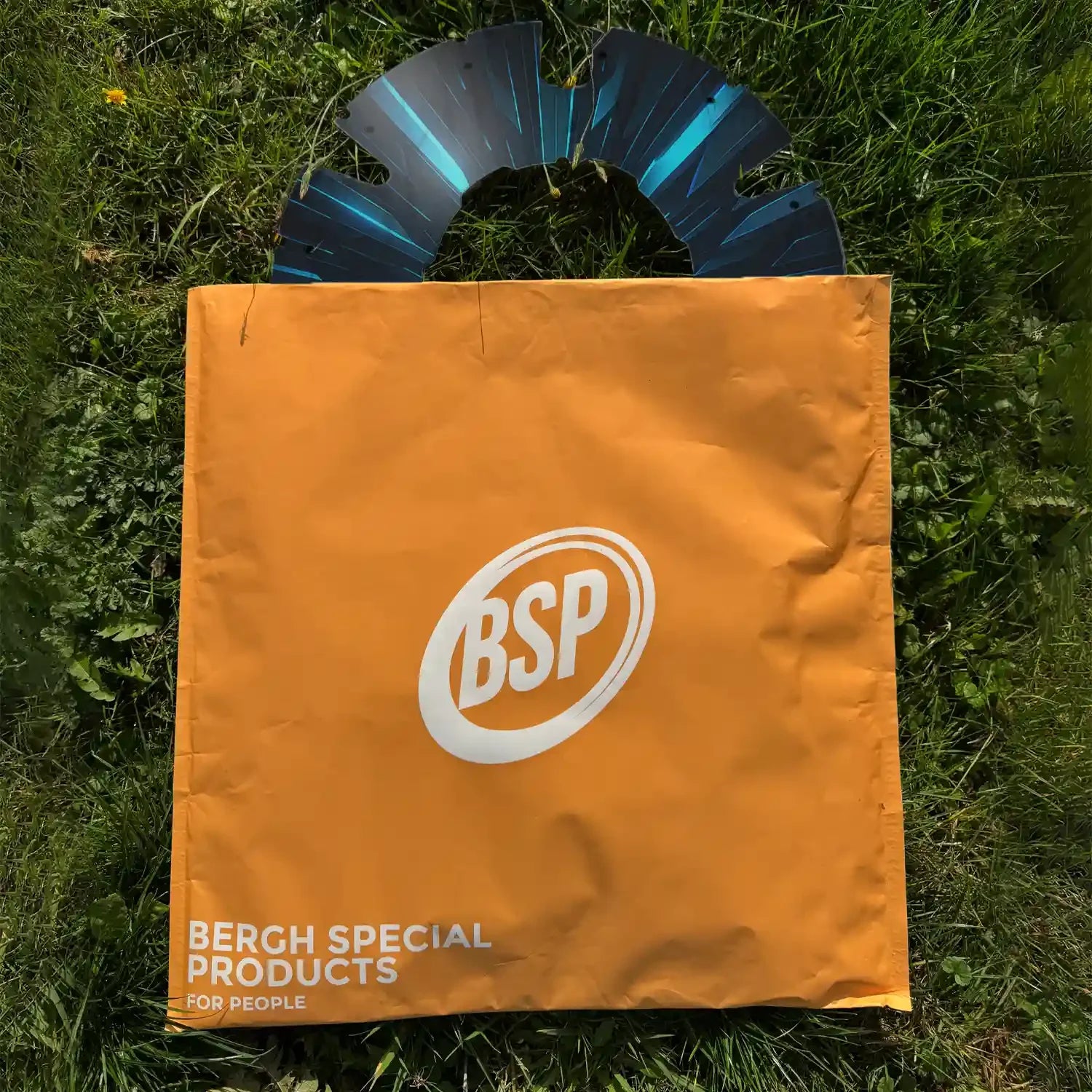 Printed wheelchair spoke guard with blue design and orange BSP packaging on grass