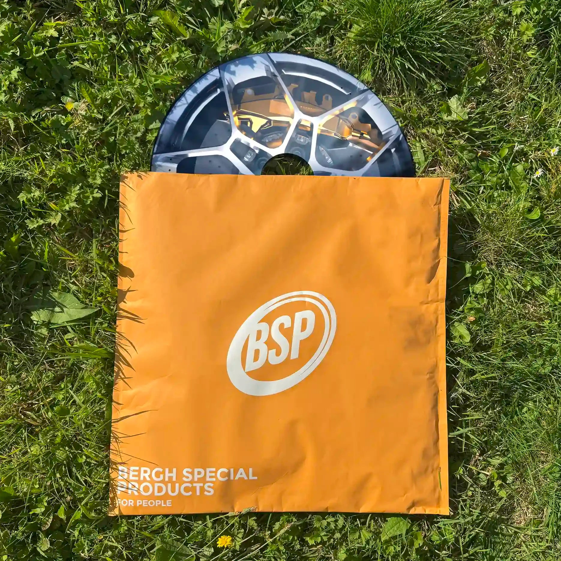 Wheelchair spoke guard partially inside orange storage bag on grass