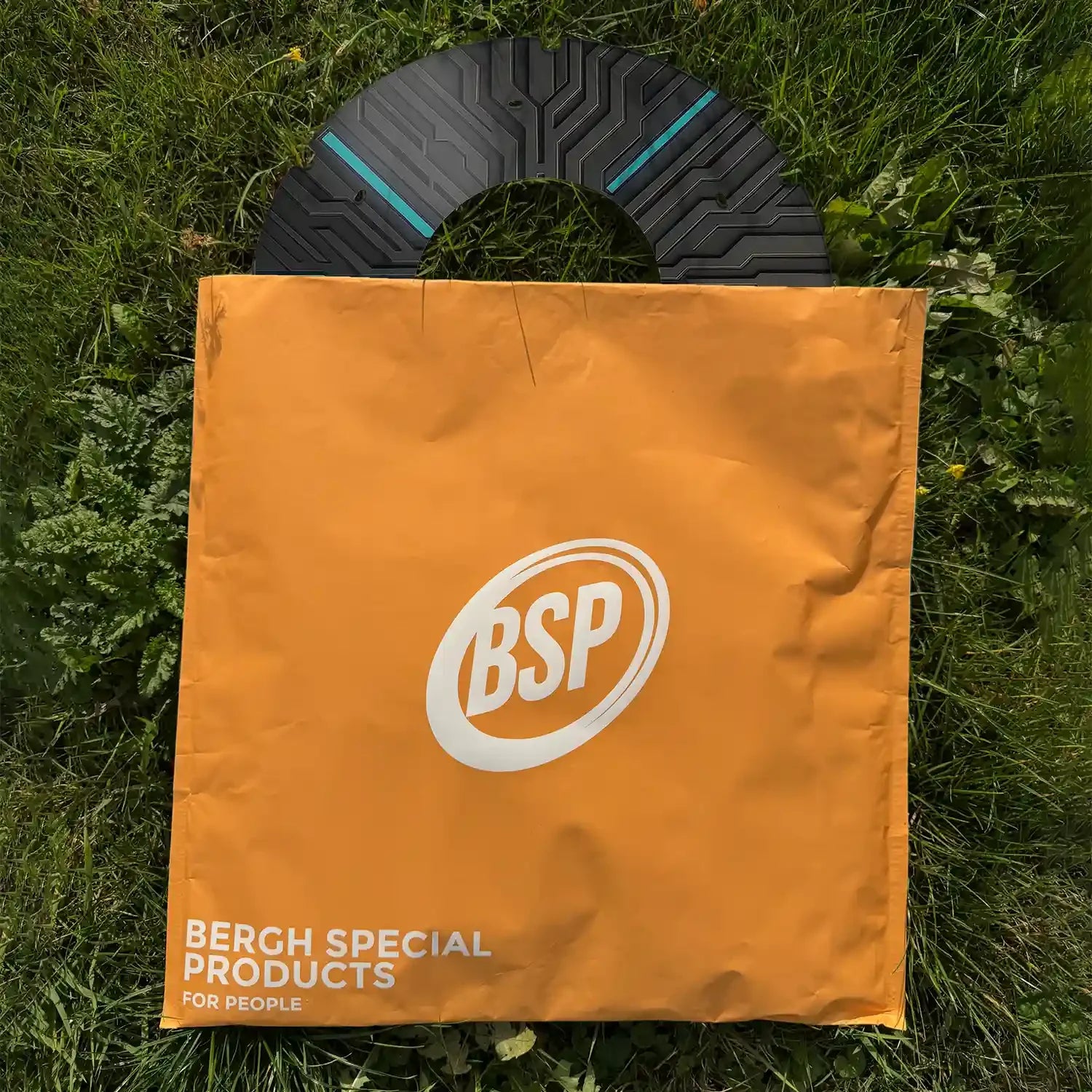 Bedruckter Rollstuhl-Speichenschutz mit Schaltkreisdesign und blauen Akzenten auf Gras, teilweise in einer orangefarbenen BSP-Tasche