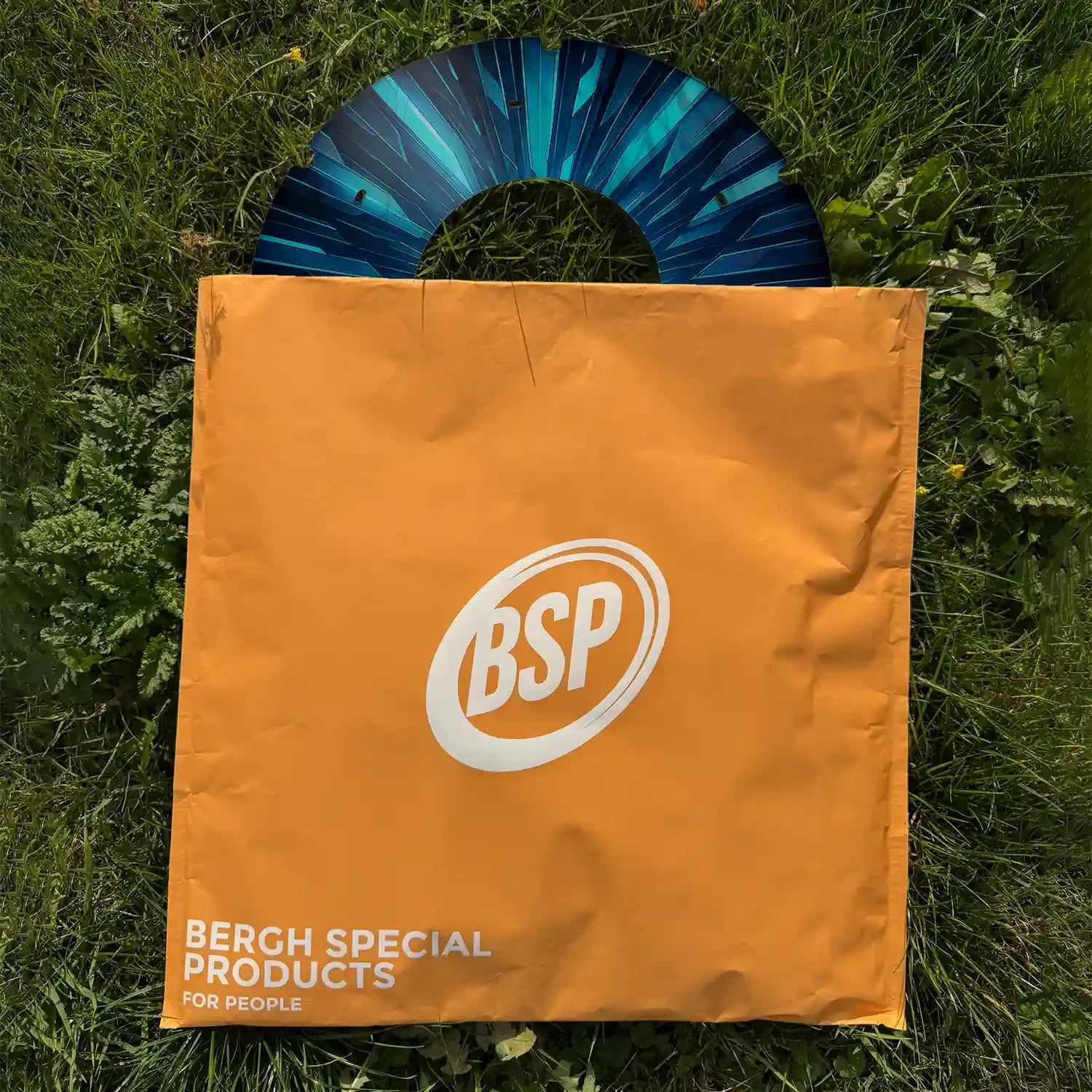 Printed wheelchair spoke guard with blue design in orange BSP bag on grass