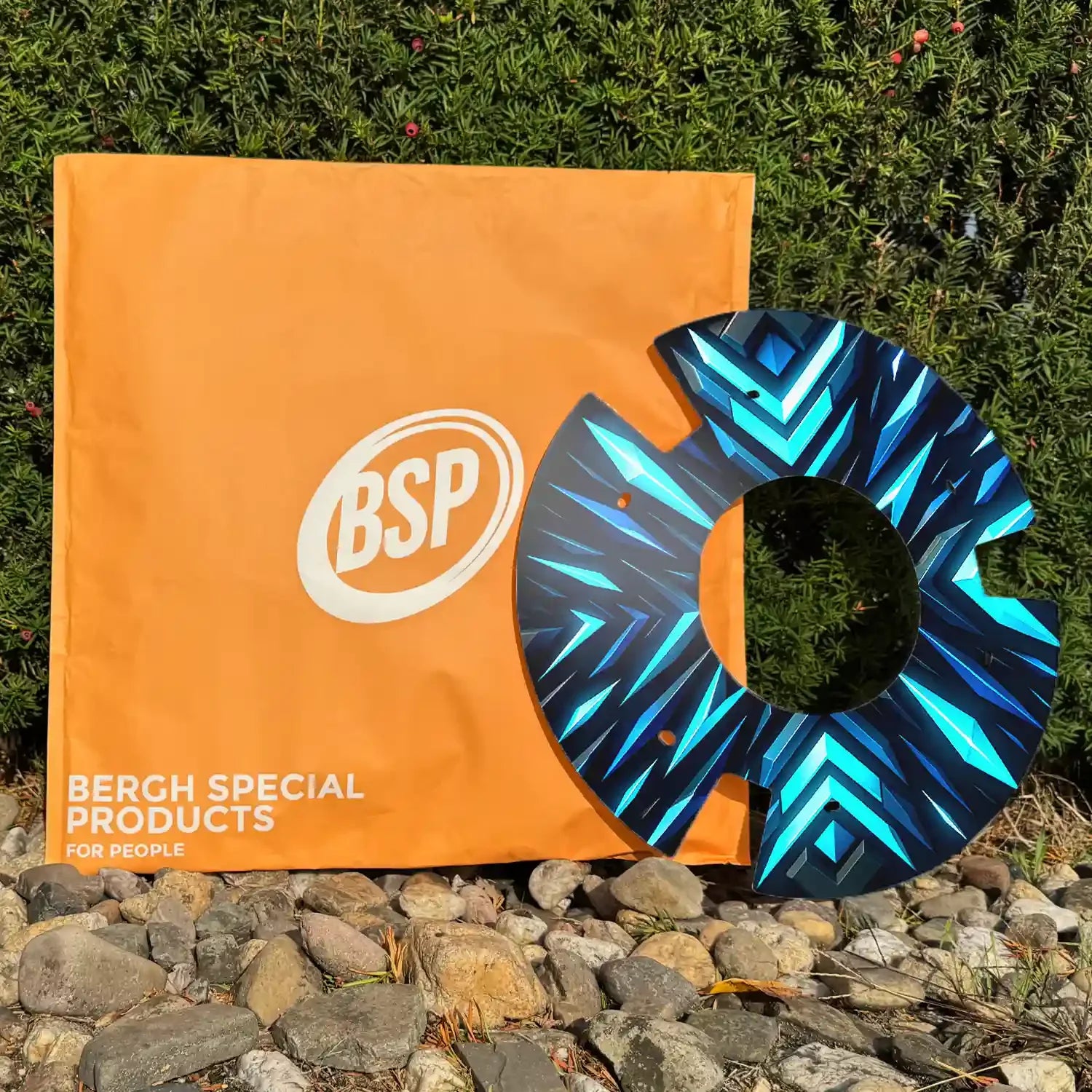 Blue geometric wheelchair spoke guard with printed cover outdoors near green bush