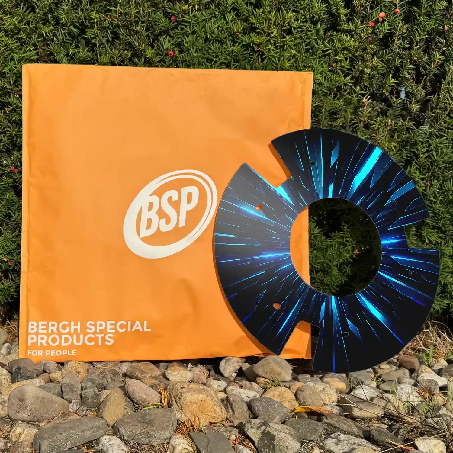 Printed wheelchair spoke guard with blue streak design displayed on rocks near green shrub and orange BSP bag.