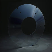 Transparent wheelchair spoke guard disc with mounting holes on a dark background