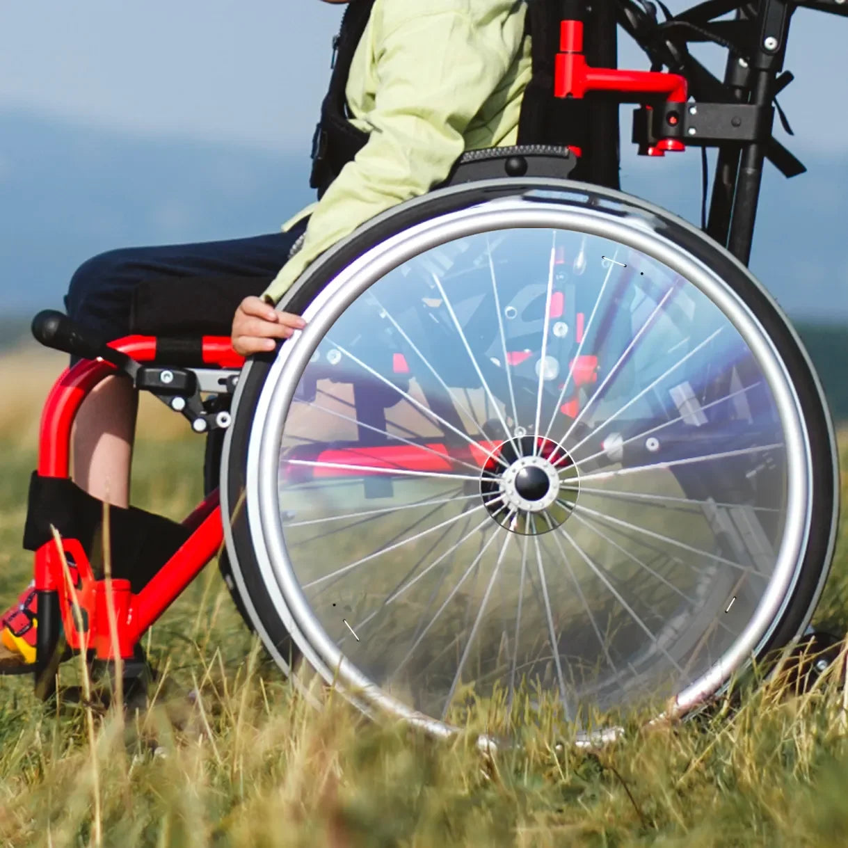 Child in outdoor wheelchair with transparent spoke guards featuring cutouts, on grass