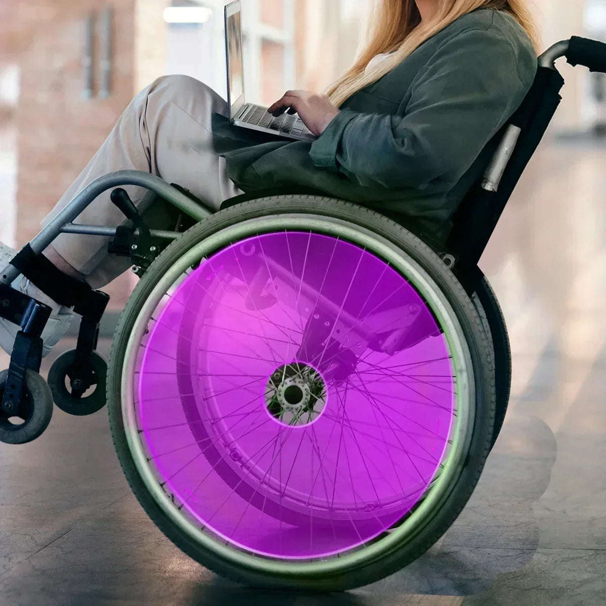 Purple wheelchair spoke guard on manual wheelchair wheel, woman using laptop
