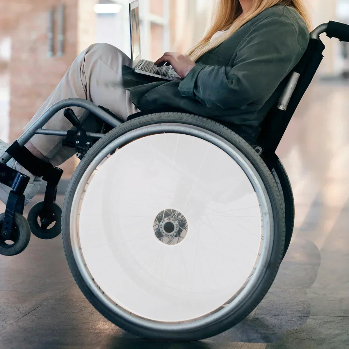 Woman using laptop in wheelchair with white spoke guards on wheels