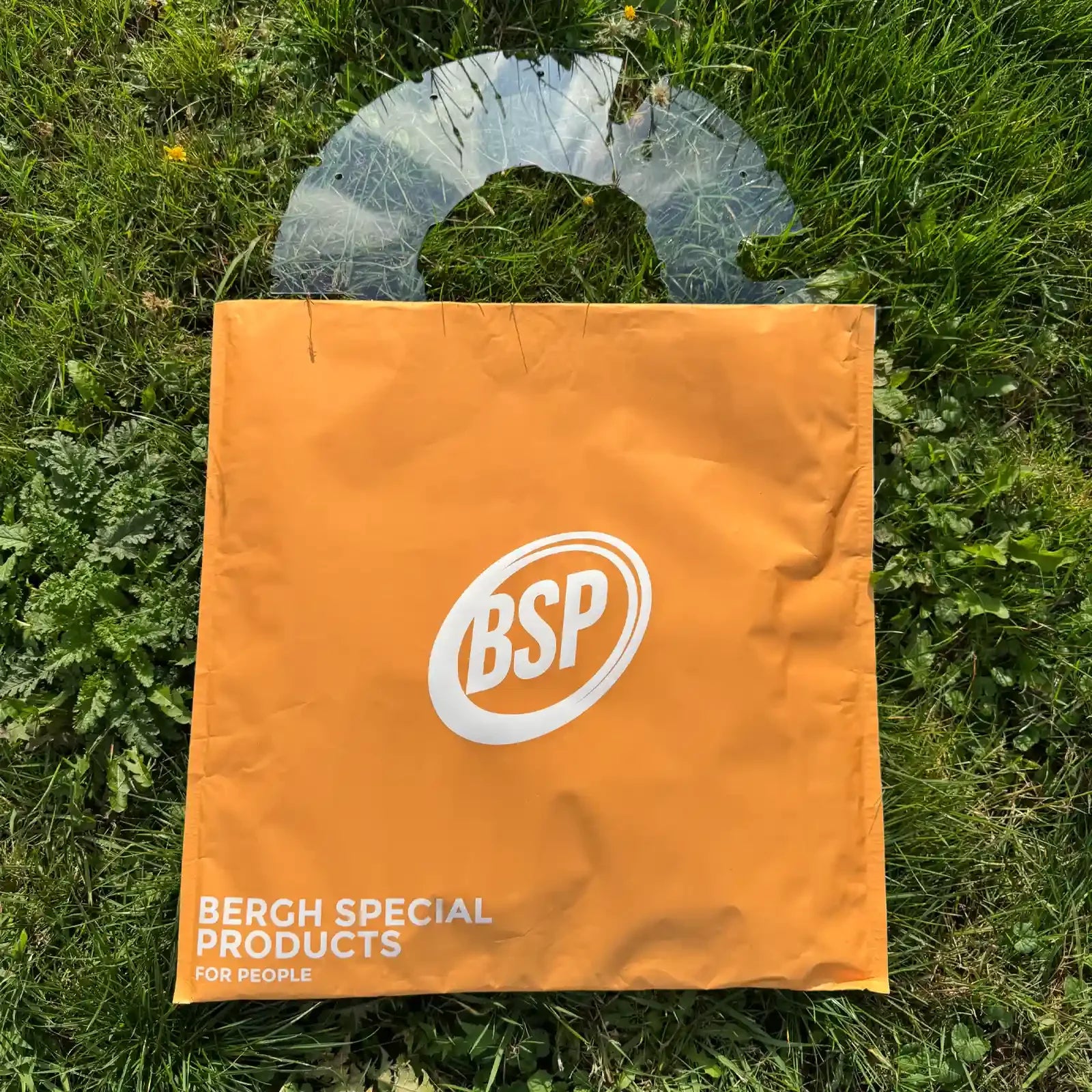 Transparent wheelchair spoke guard on grass behind orange BSP branded cover