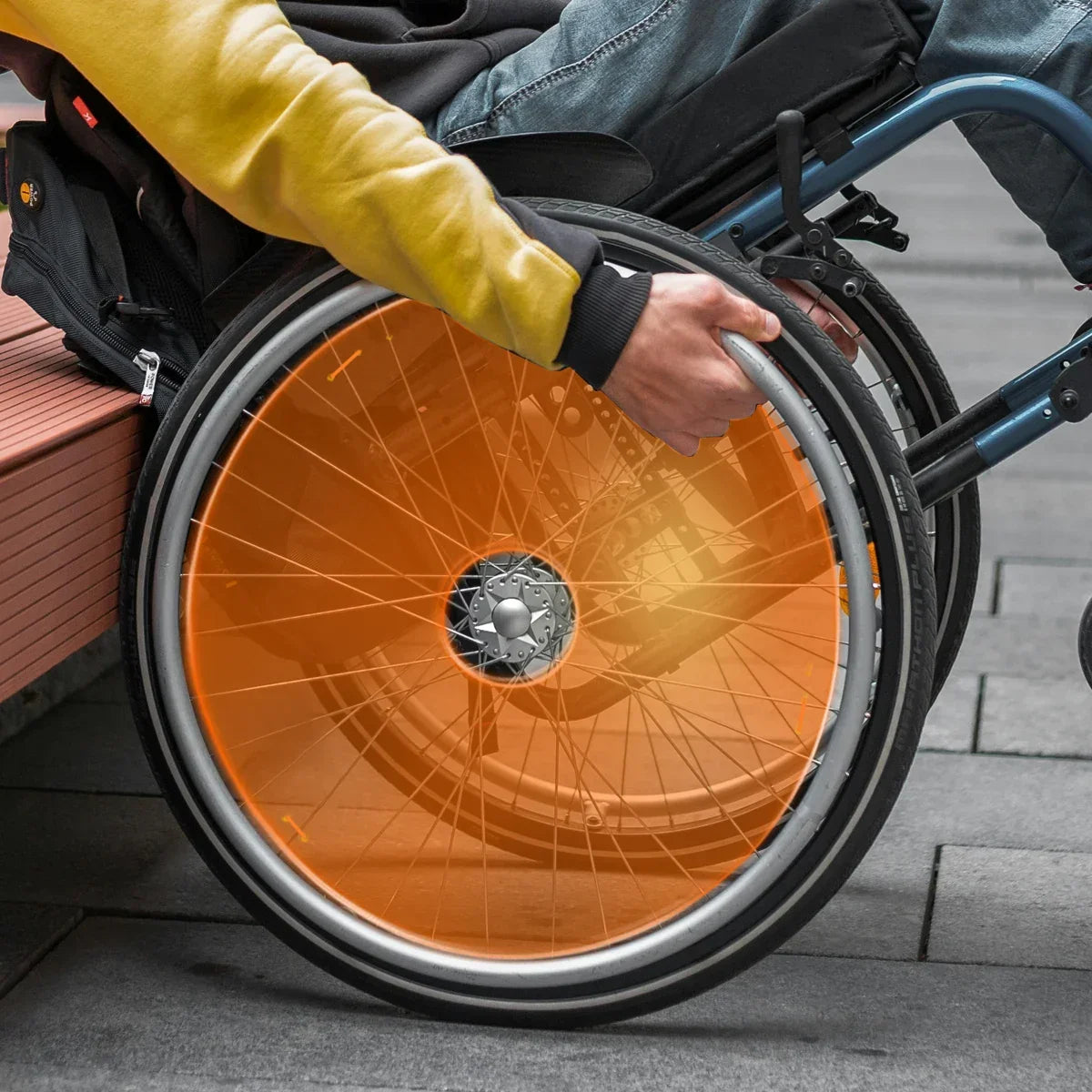 Man in wheelchair with bright orange neon spoke guards outdoors