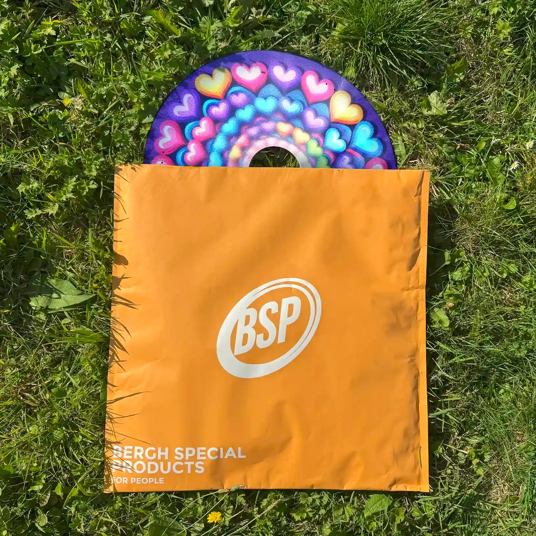 Colorful spiral hearts wheelchair spoke guard partially in orange BSP bag on grass