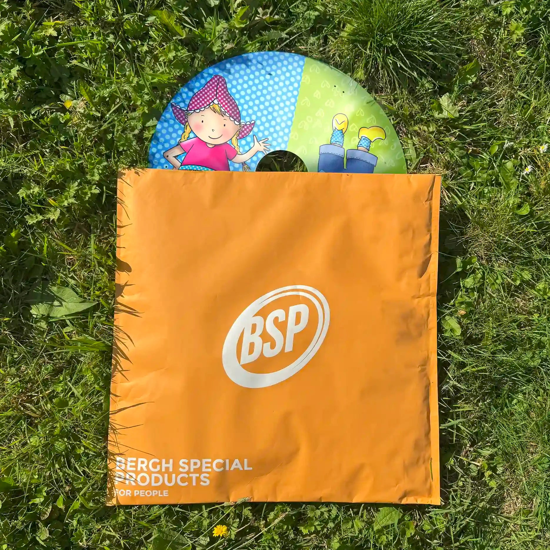 Colorful wheelchair spoke guard with cartoon character, half-out of orange BSP bag on grass
