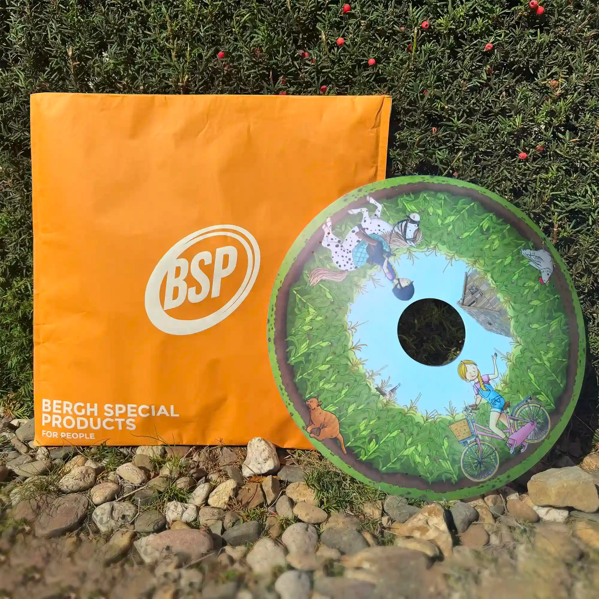 Colorful wheelchair spoke guard with pony and cornfield illustration, displayed outdoors near orange packaging.