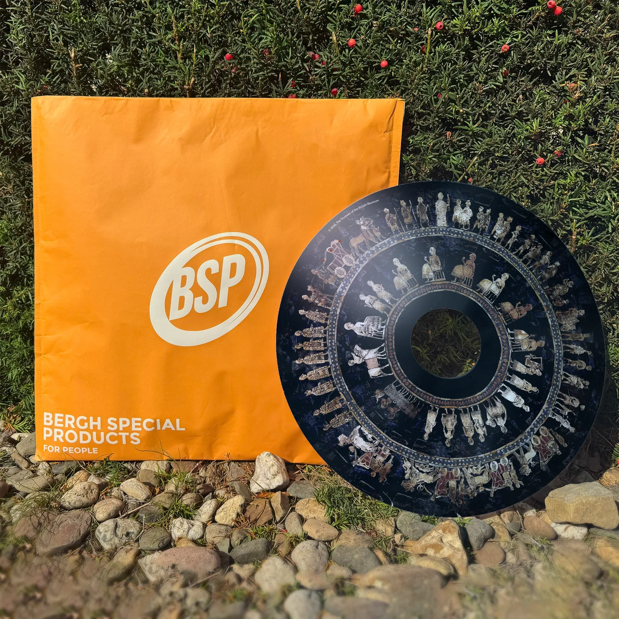 Dekorativer Rollstuhl-Speichenschutz mit antiken Figuren neben orangefarbener BSP-Verpackung im Freien