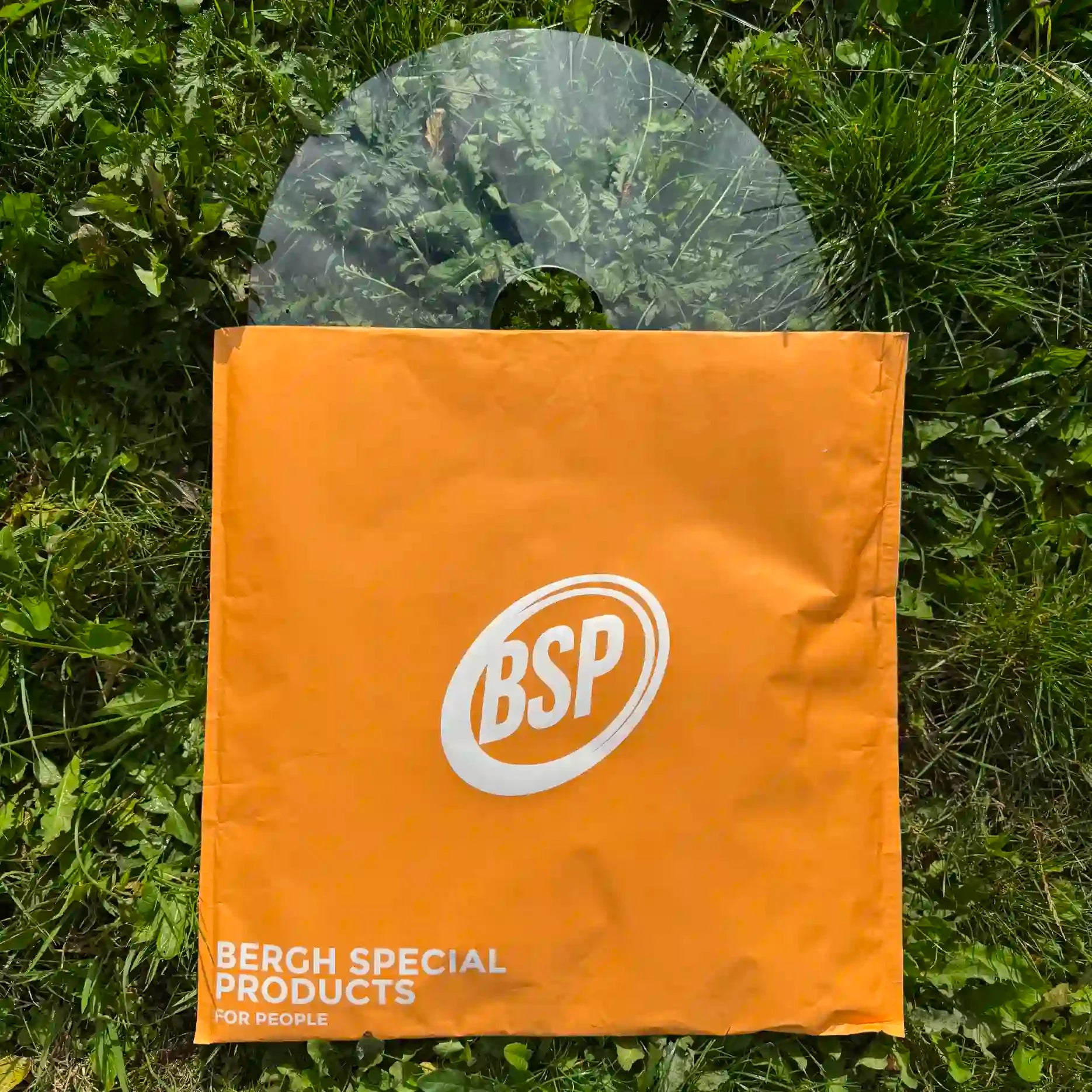Transparent wheelchair spoke guard on grass behind an orange BSP branded bag