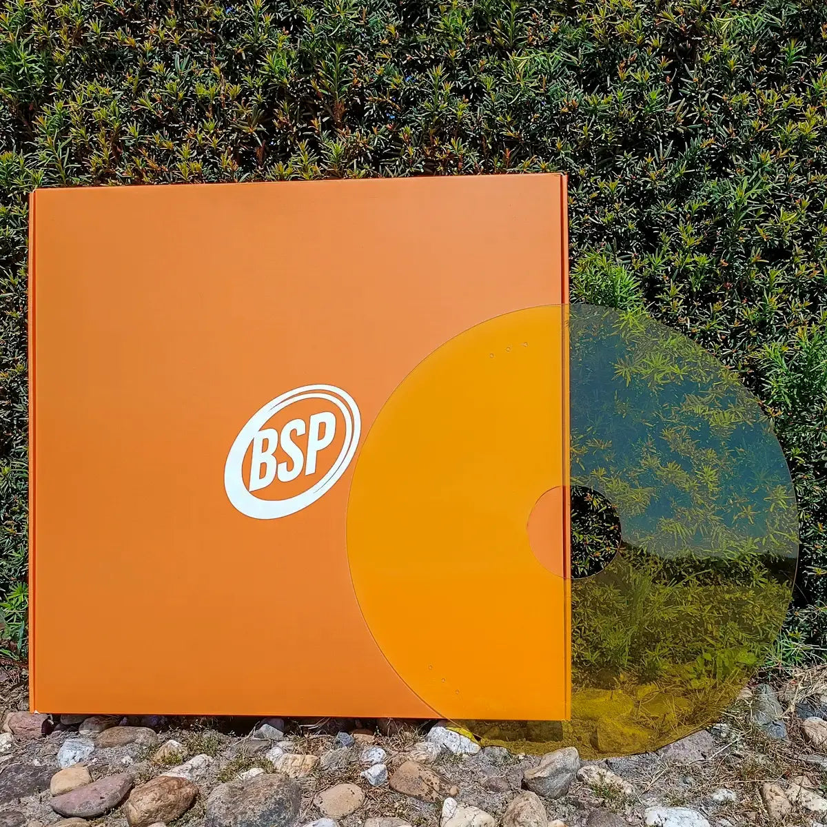 Yellow wheelchair spoke guard on stones near green wall, bold BSP logo visible on packaging