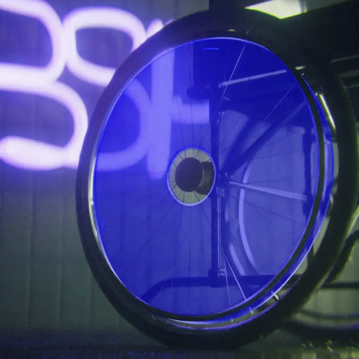Blue wheelchair wheel with spoke guard under neon light, durable mobility accessory for everyday use