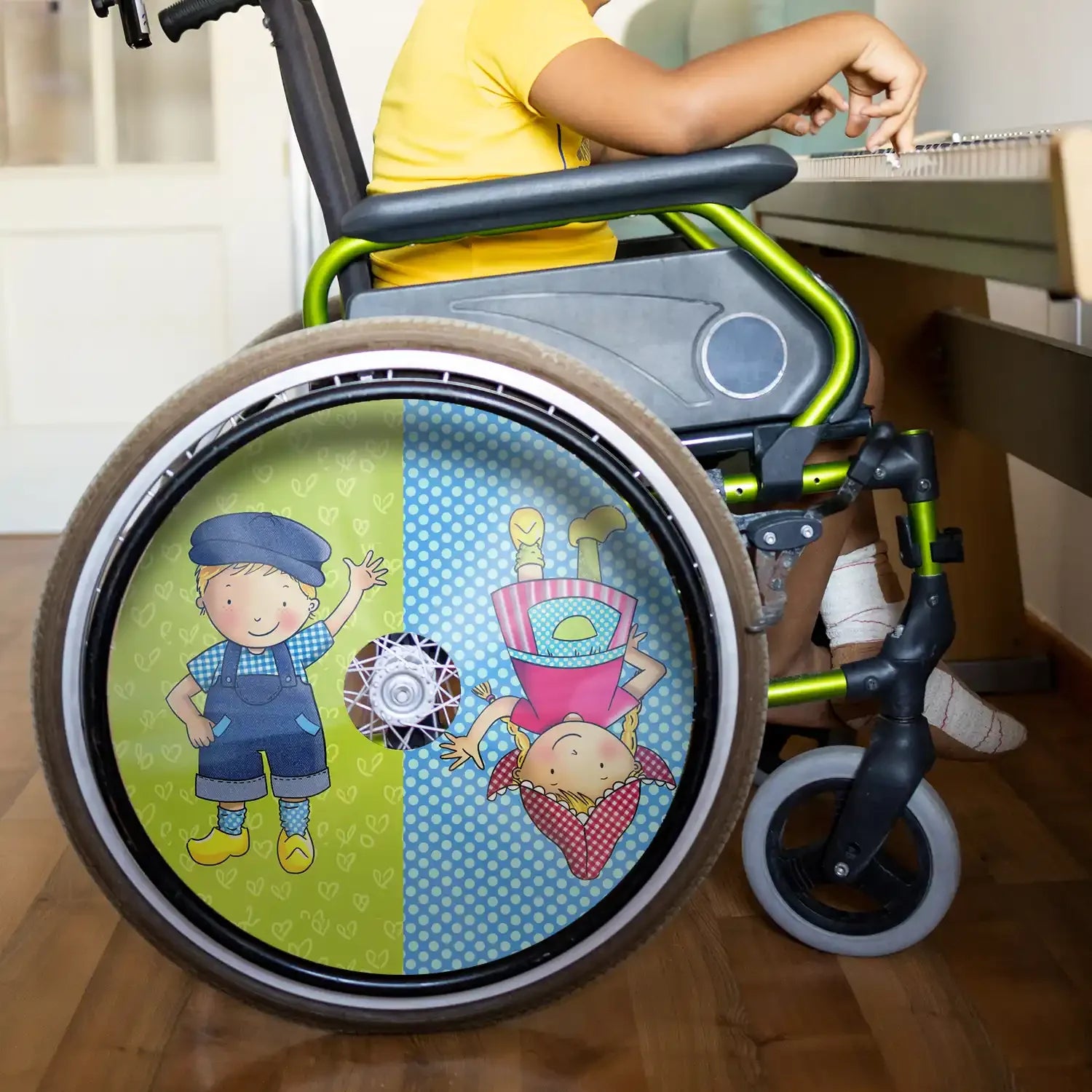 Child in wheelchair with colorful spoke guards, cartoon boy and girl design, indoor setting
