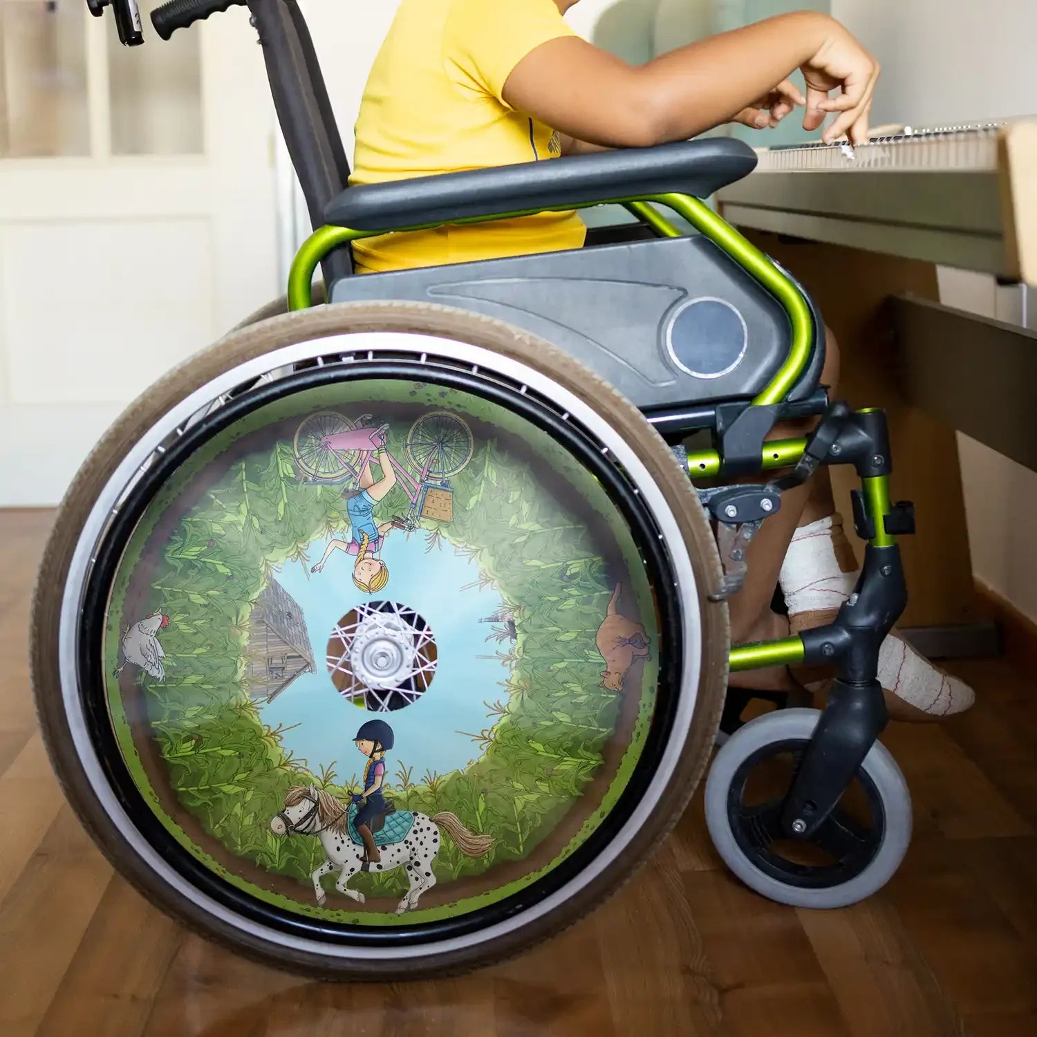 Child in wheelchair with colorful spoke guard featuring pony and cornfield illustration.