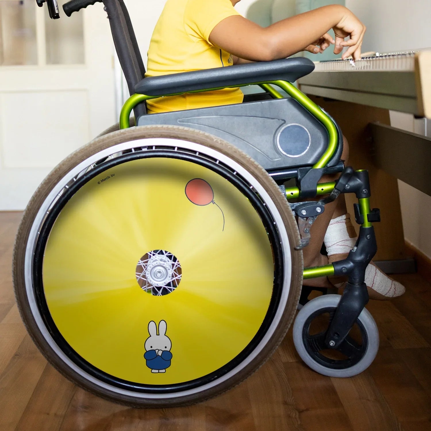 Child in wheelchair with yellow Miffy design spoke guard and red balloon graphic