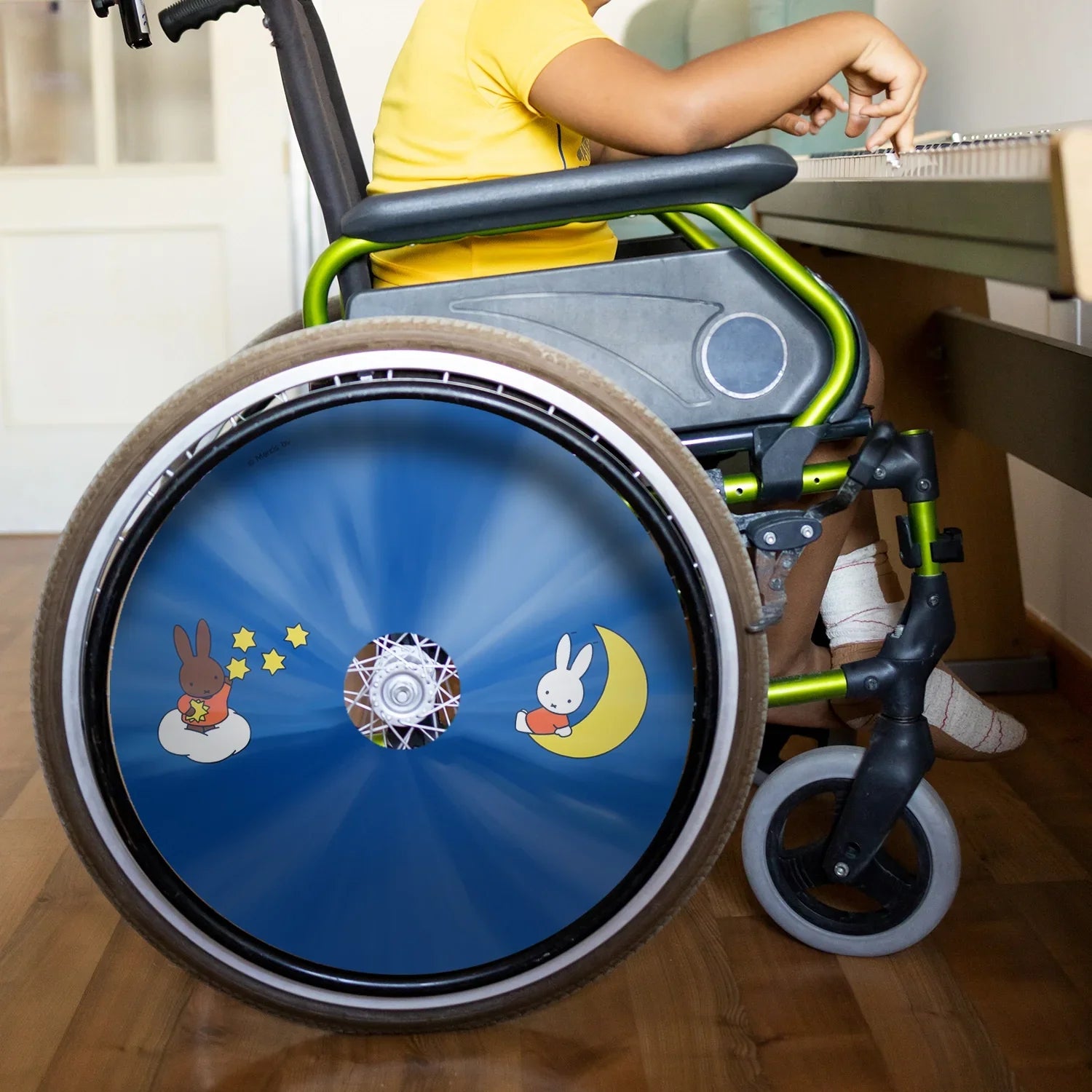 Child in wheelchair with colorful Miffy-themed spoke guard and cartoon moon and stars