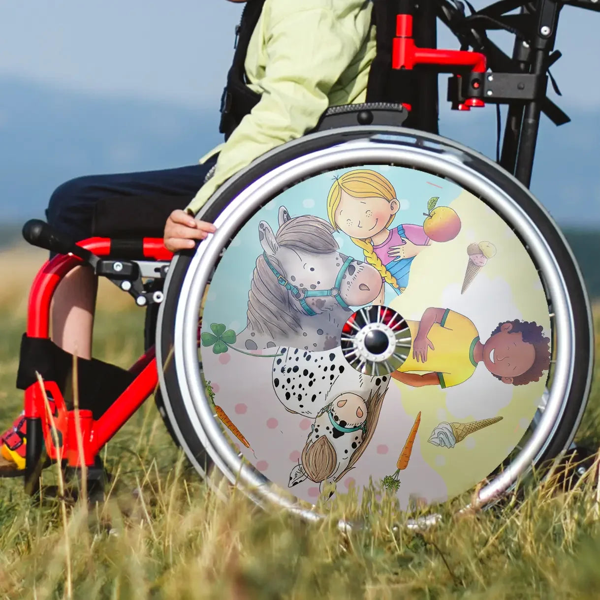 Boy in wheelchair with colorful spoke guard featuring cartoon children and ponies outdoors