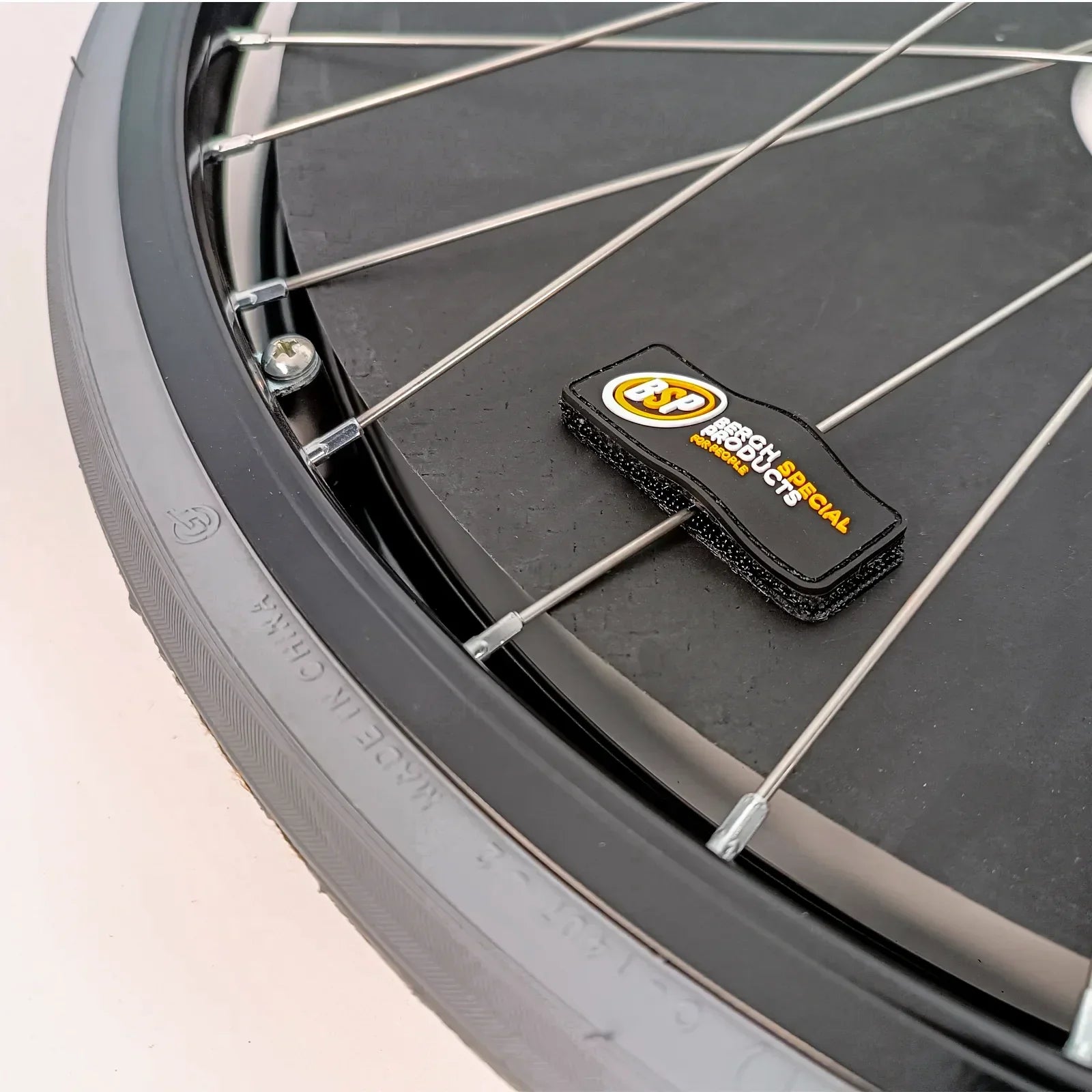 Black wheelchair spoke guard with branded tag, protecting wheel spokes for safety and durability.