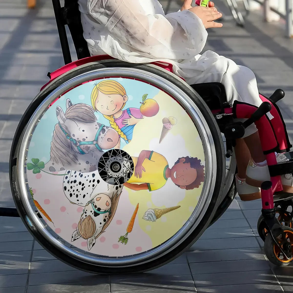 Child in wheelchair with colorful spoke guard featuring cartoon children and horses