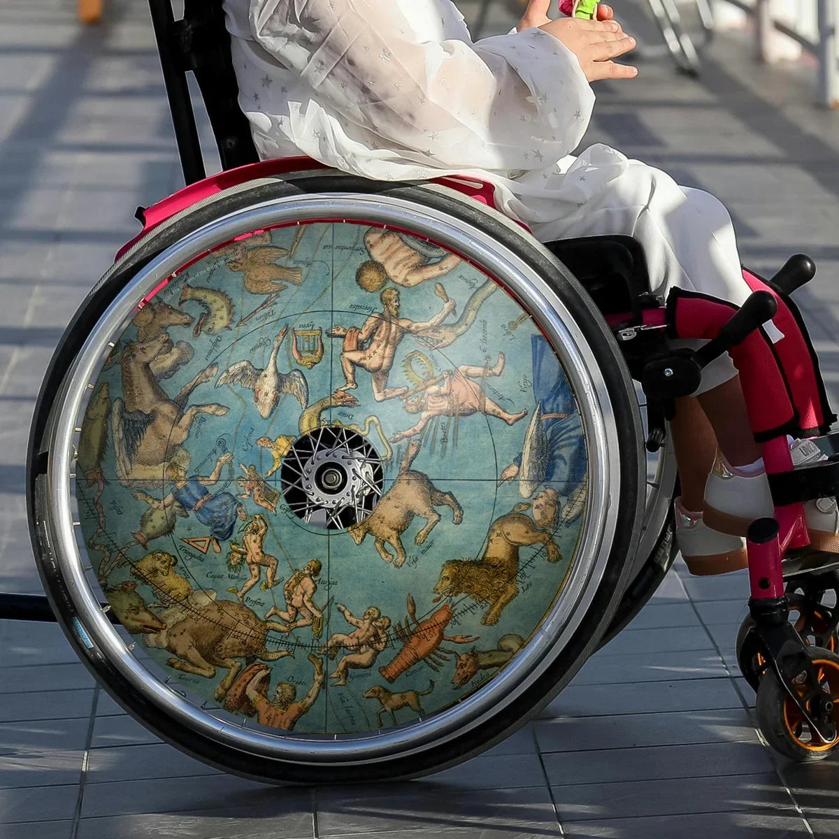 Girl in wheelchair with celestial globe spoke guards on wheel, durable wheelchair accessory