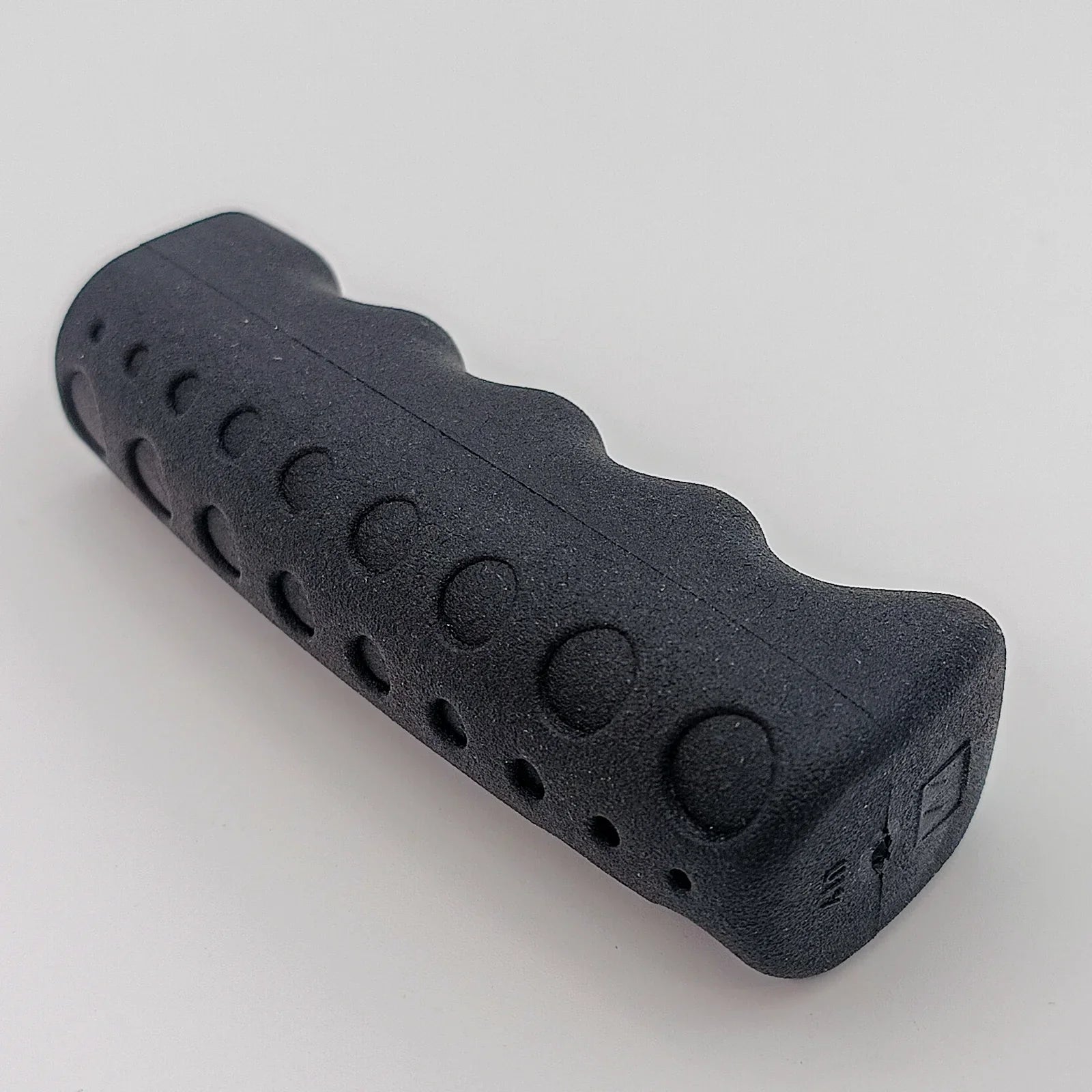 Black ergonomic wheelchair hand grip with textured surface for secure hold