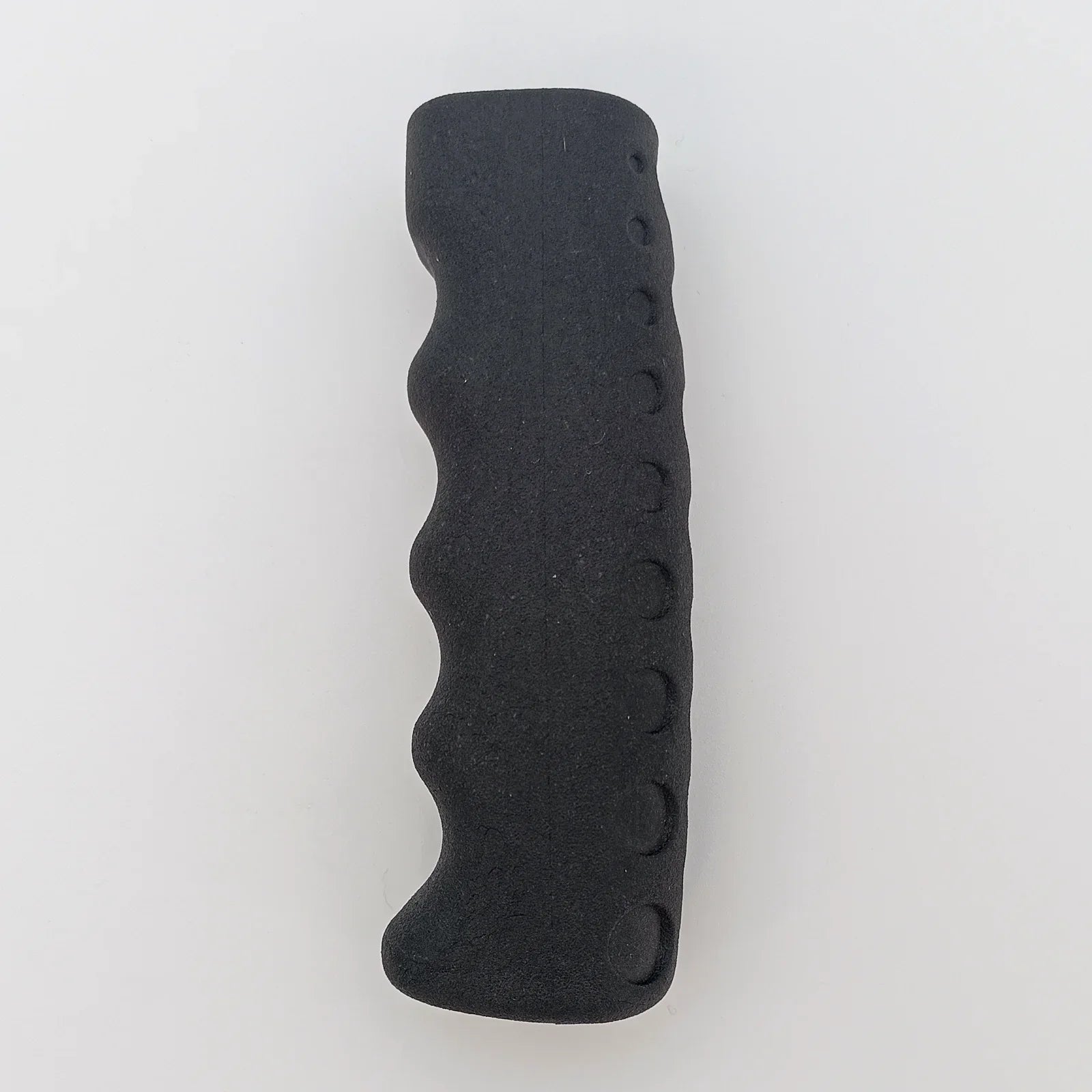 Black ergonomic wheelchair hand grip with textured surface and finger holes for secure hold