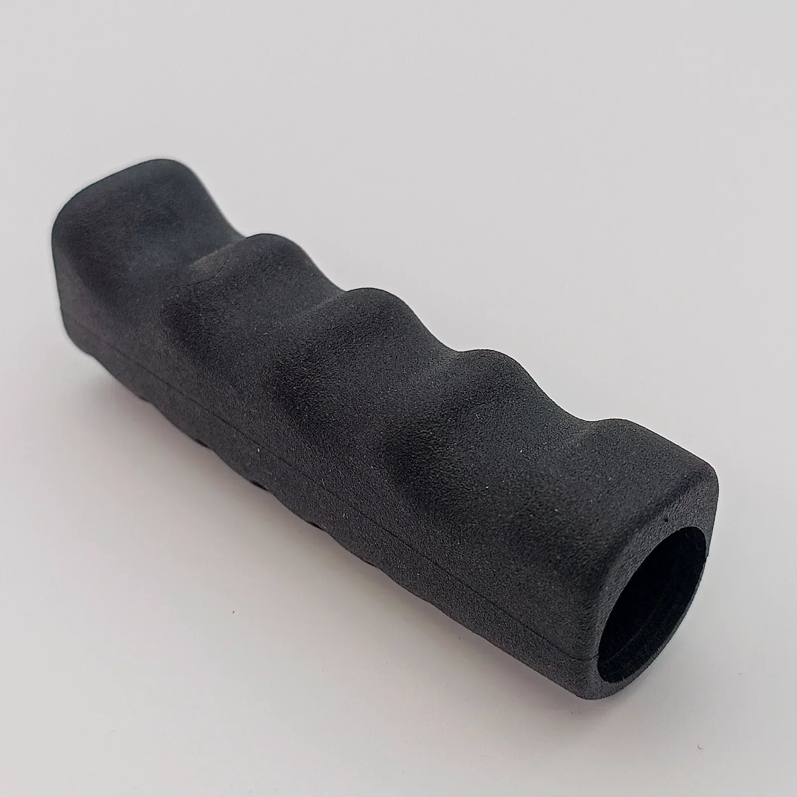 Black ergonomic wheelchair handle grip with textured surface for secure hold