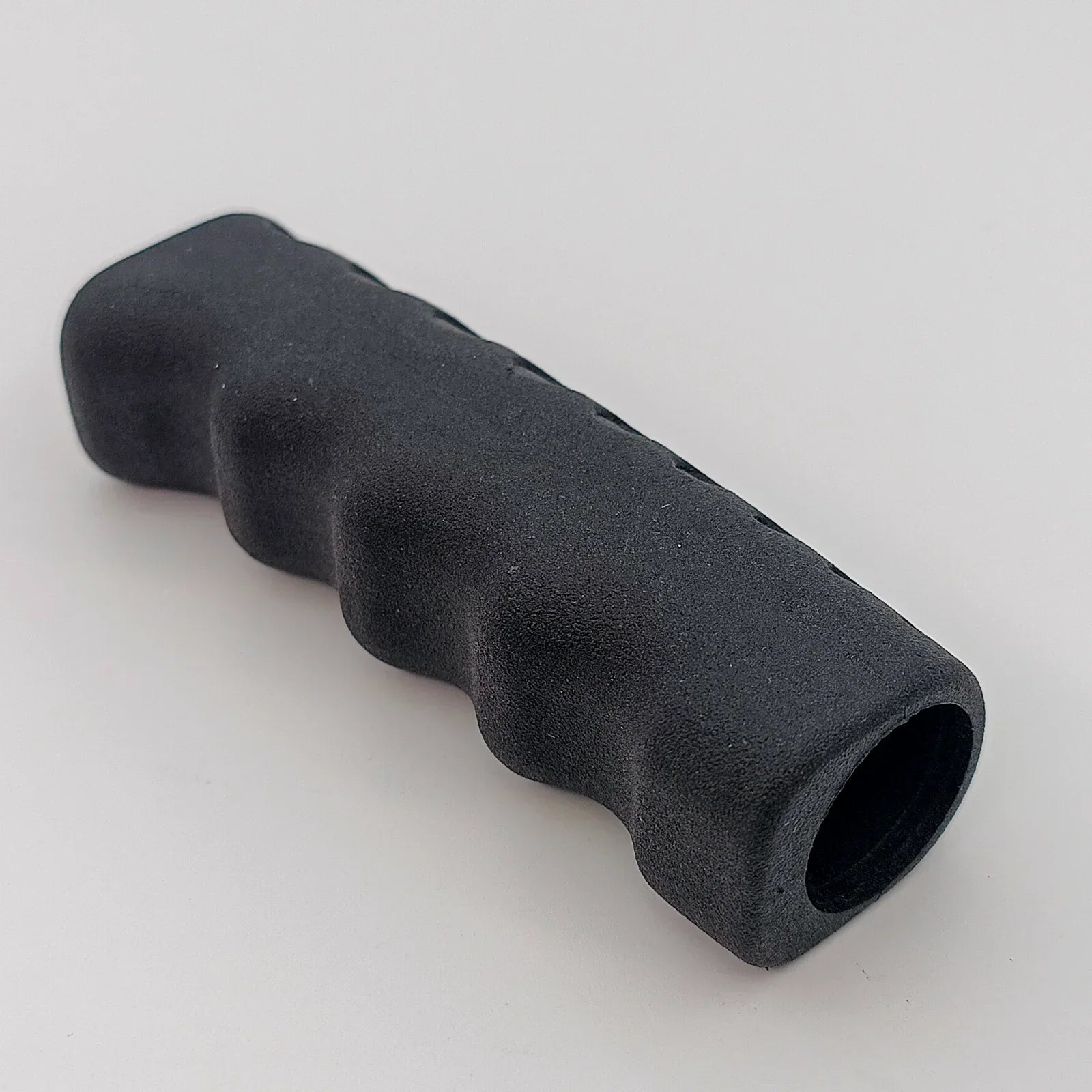 Black ergonomic wheelchair handle grip with textured surface for secure hold