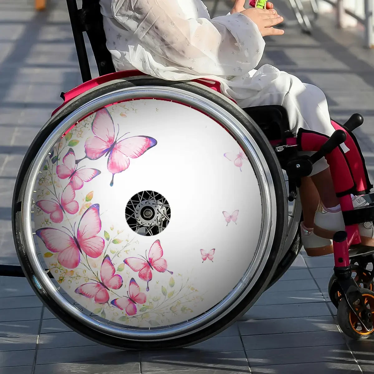 Kids wheelchair with pink butterfly spoke guard, stylish wheelchair accessory outdoors