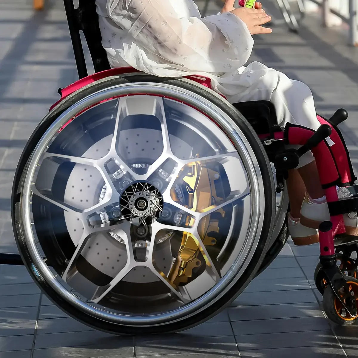 Child in a wheelchair with custom car wheel design spoke guard on wheel