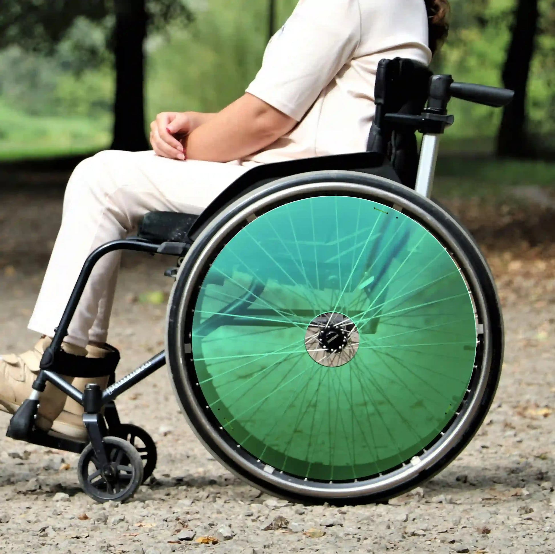 Woman in wheelchair outdoors with bright green spoke guards on rear wheels