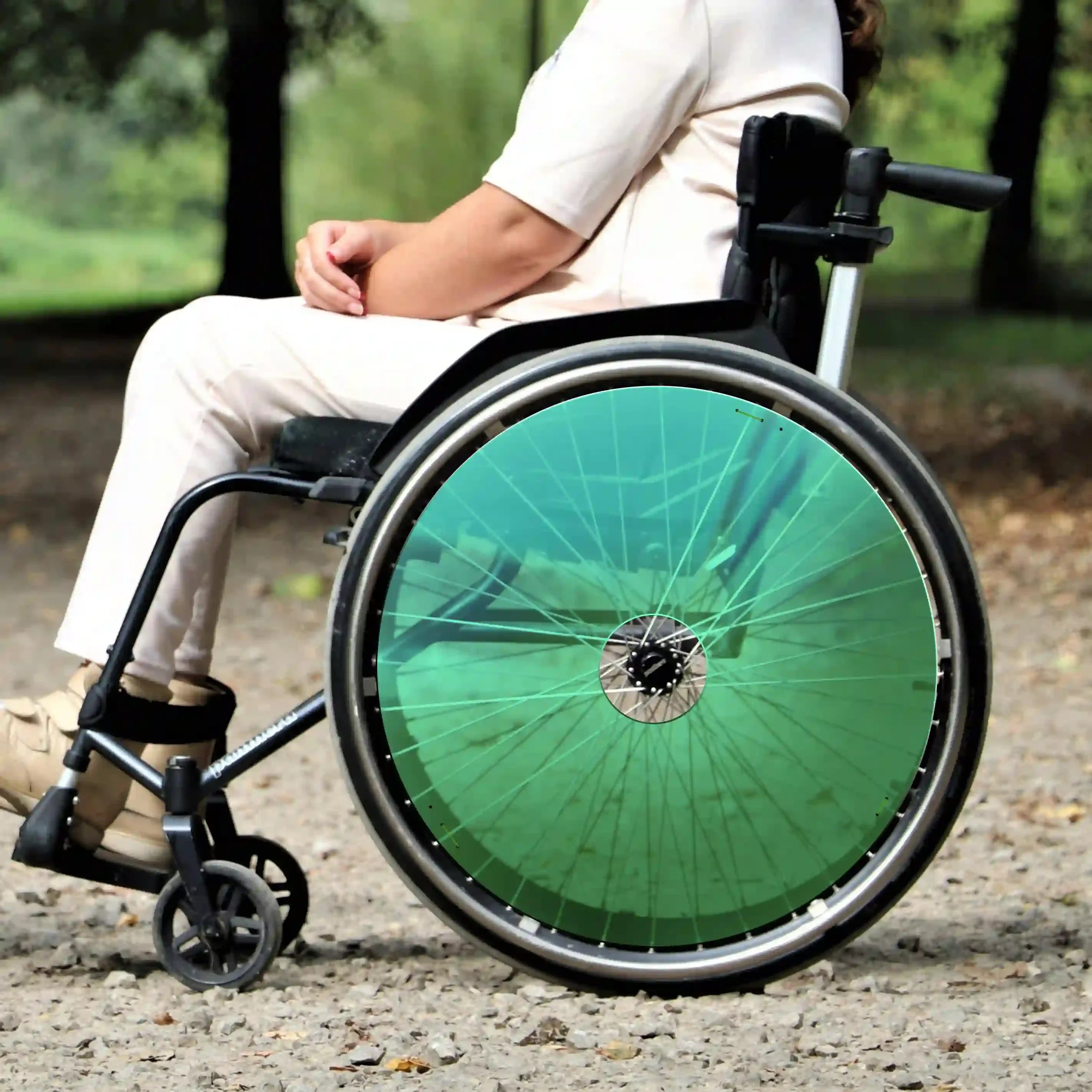 Woman in wheelchair outdoors with bright green spoke guards on rear wheels