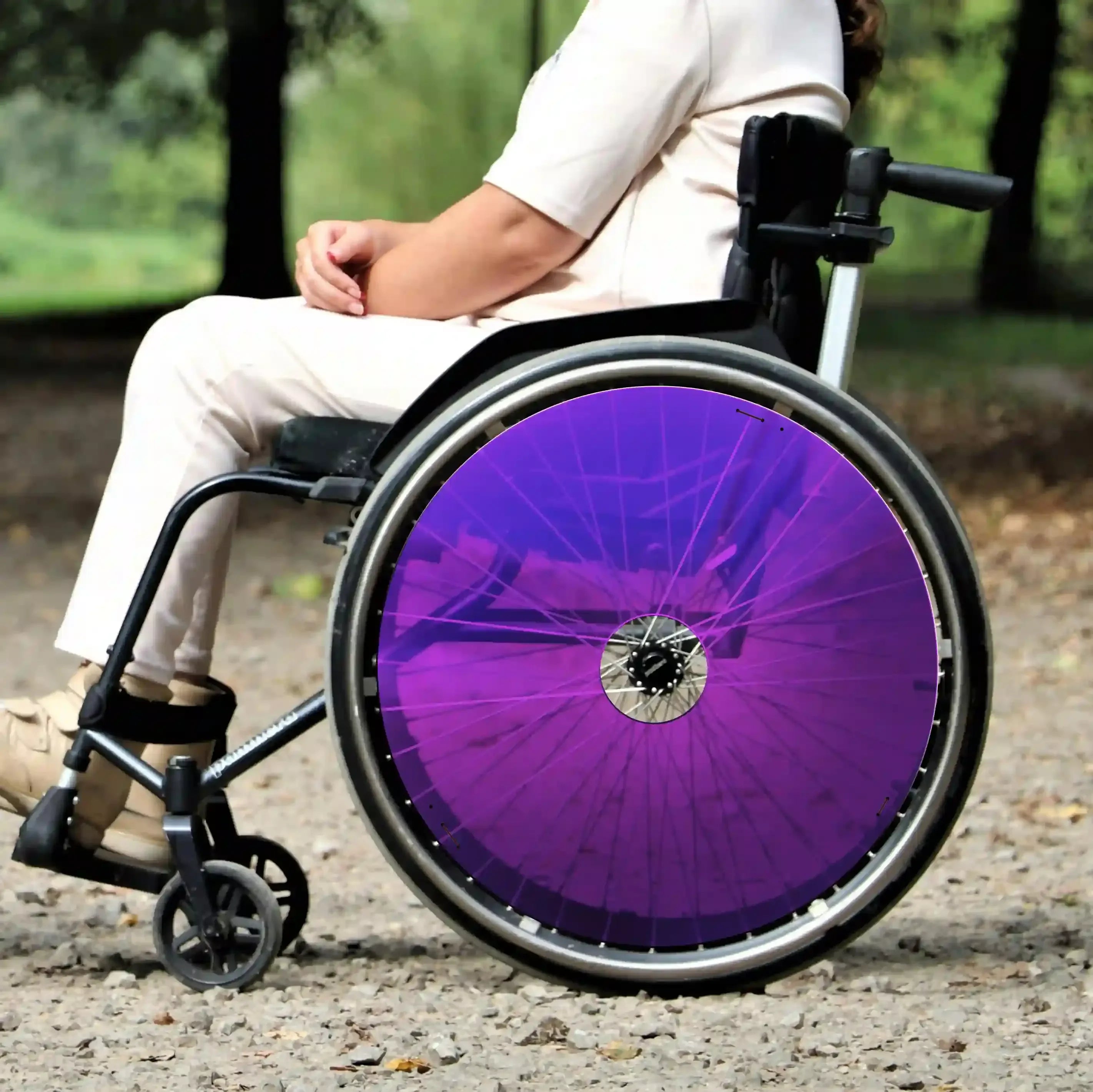 Woman sitting in wheelchair with vibrant purple spoke guards outdoors