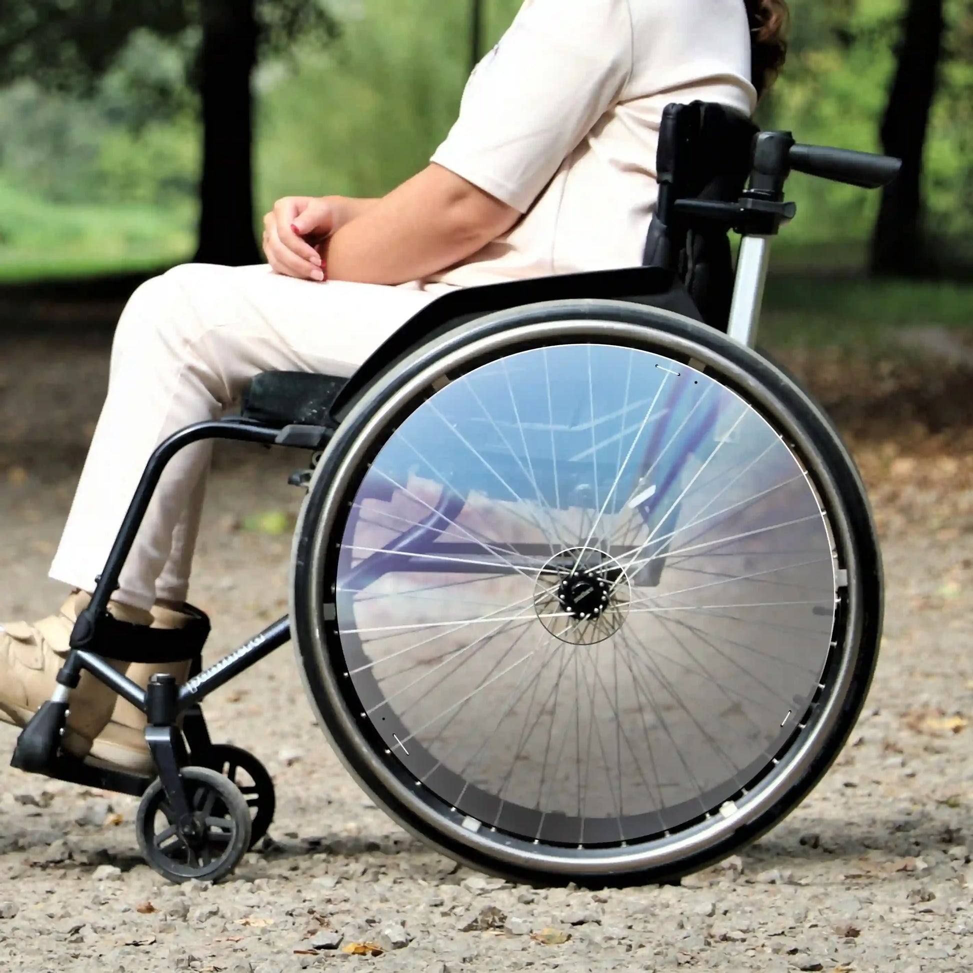 Woman outdoors in a wheelchair with clear spoke guards on rear wheels, accessible design