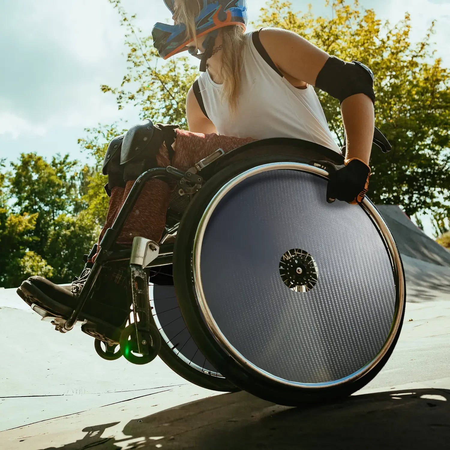 Active woman in wheelchair with carbon spoke guards at outdoor skate park