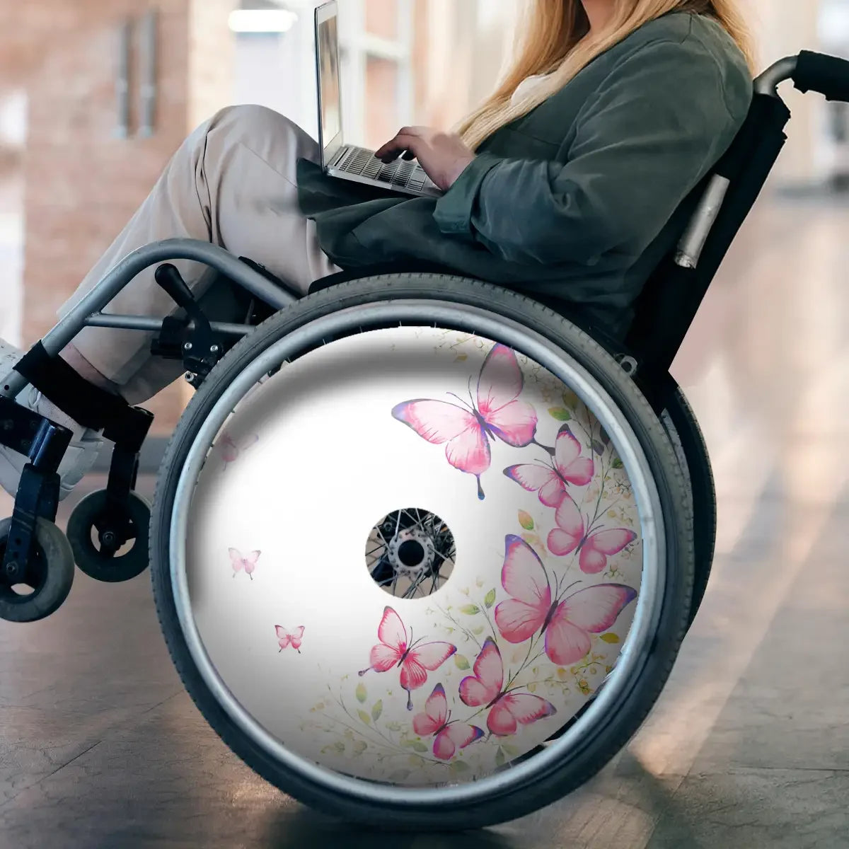 Wheelchair with butterfly print spoke guard, woman using laptop, indoor setting