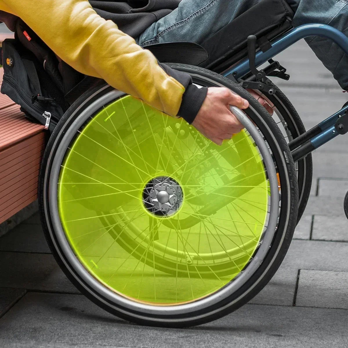 Bright green wheelchair spoke guard on manual wheelchair wheel, enhancing safety and style for daily mobility.