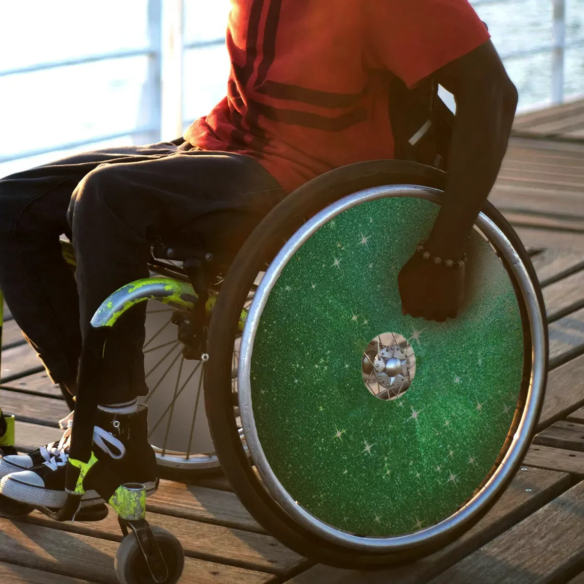 Green glitter wheelchair spoke guard on outdoor deck, durable accessory for mobility users