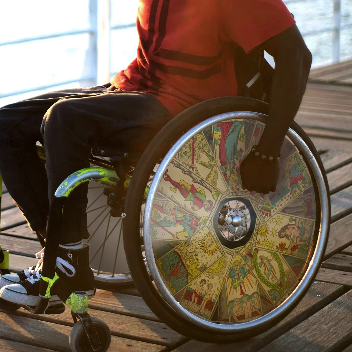 Man outdoors in wheelchair with colorful tarot card themed spoke guards on wheels