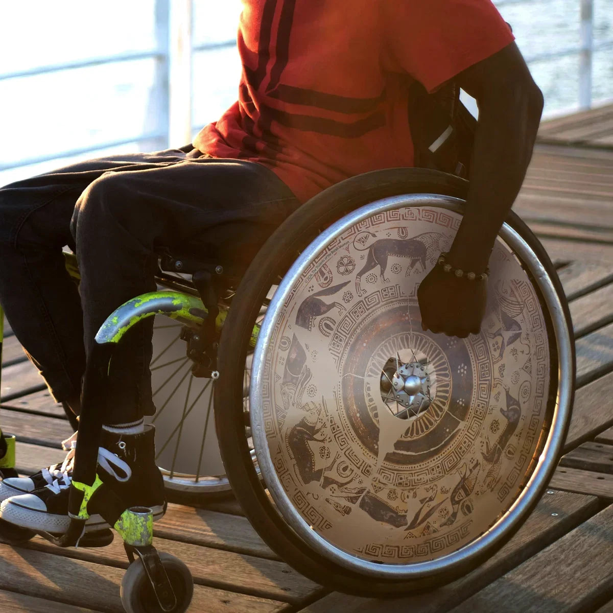 Man in wheelchair with decorative wild goat spoke guard, outdoors on wooden deck