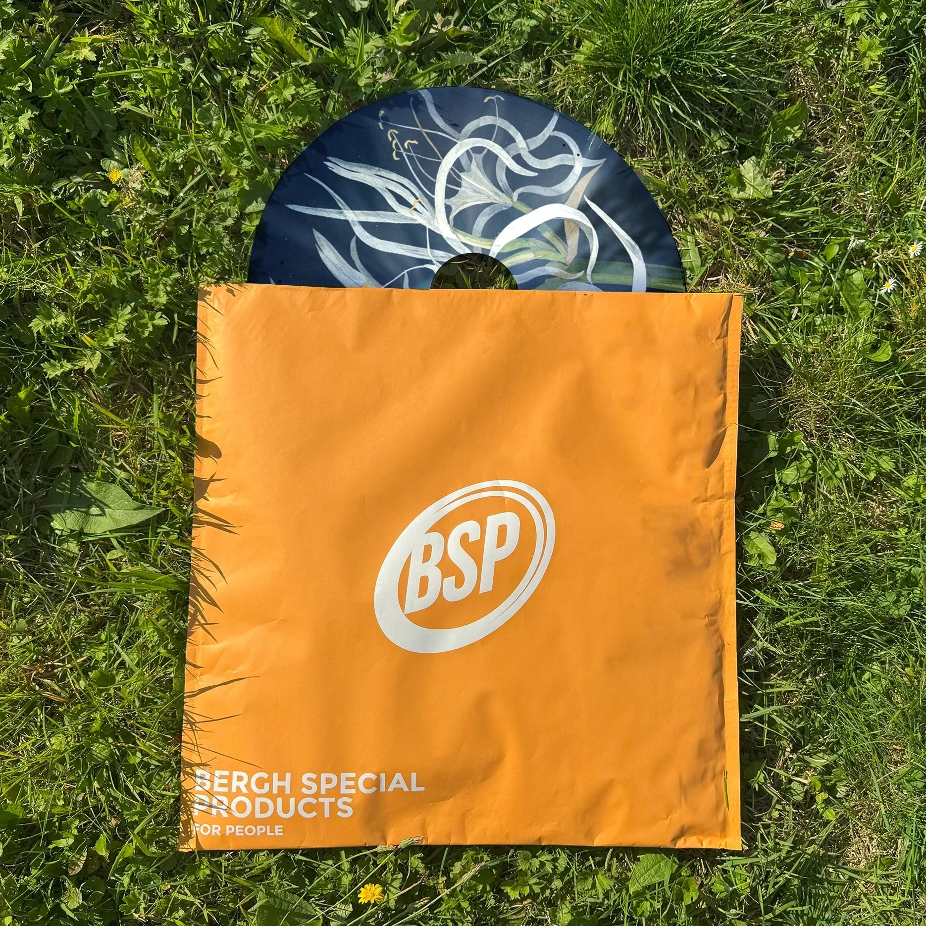 Wheelchair spoke guard with sea daffodil design partially in orange bag on grass