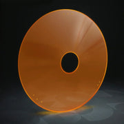 Neon orange wheelchair spoke guard with circular cutout, viewed on a dark background.