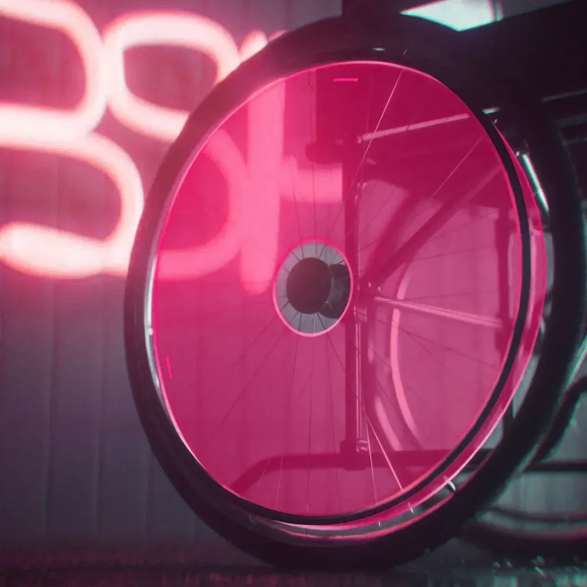 Wheelchair wheel with pink spoke guard under neon light, durable accessory for mobility