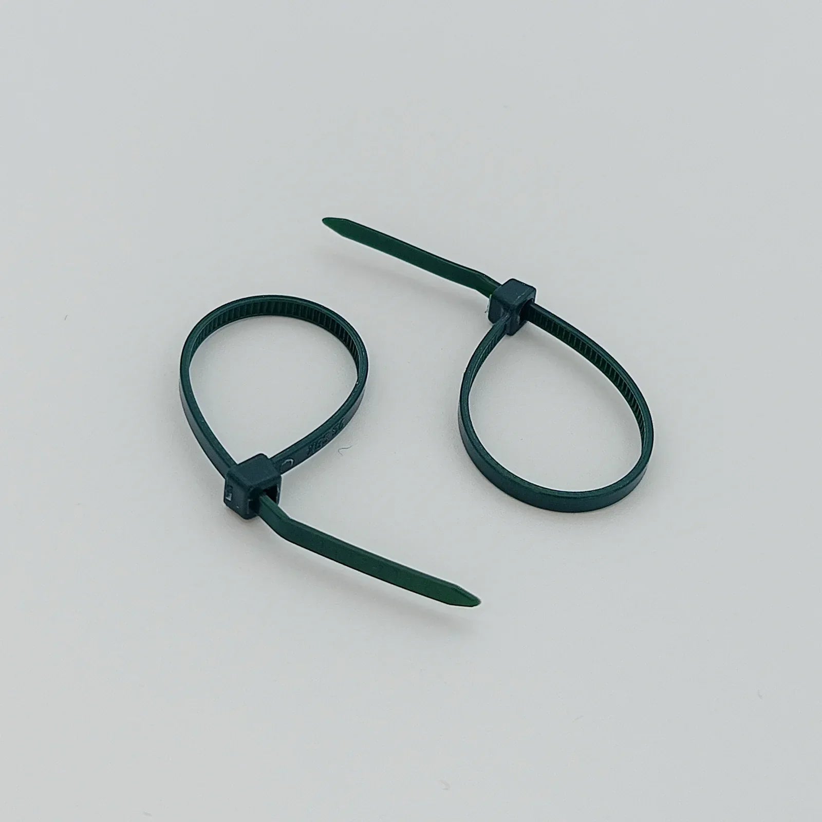 Two dark green plastic cable ties for securing wheelchair accessories and parts