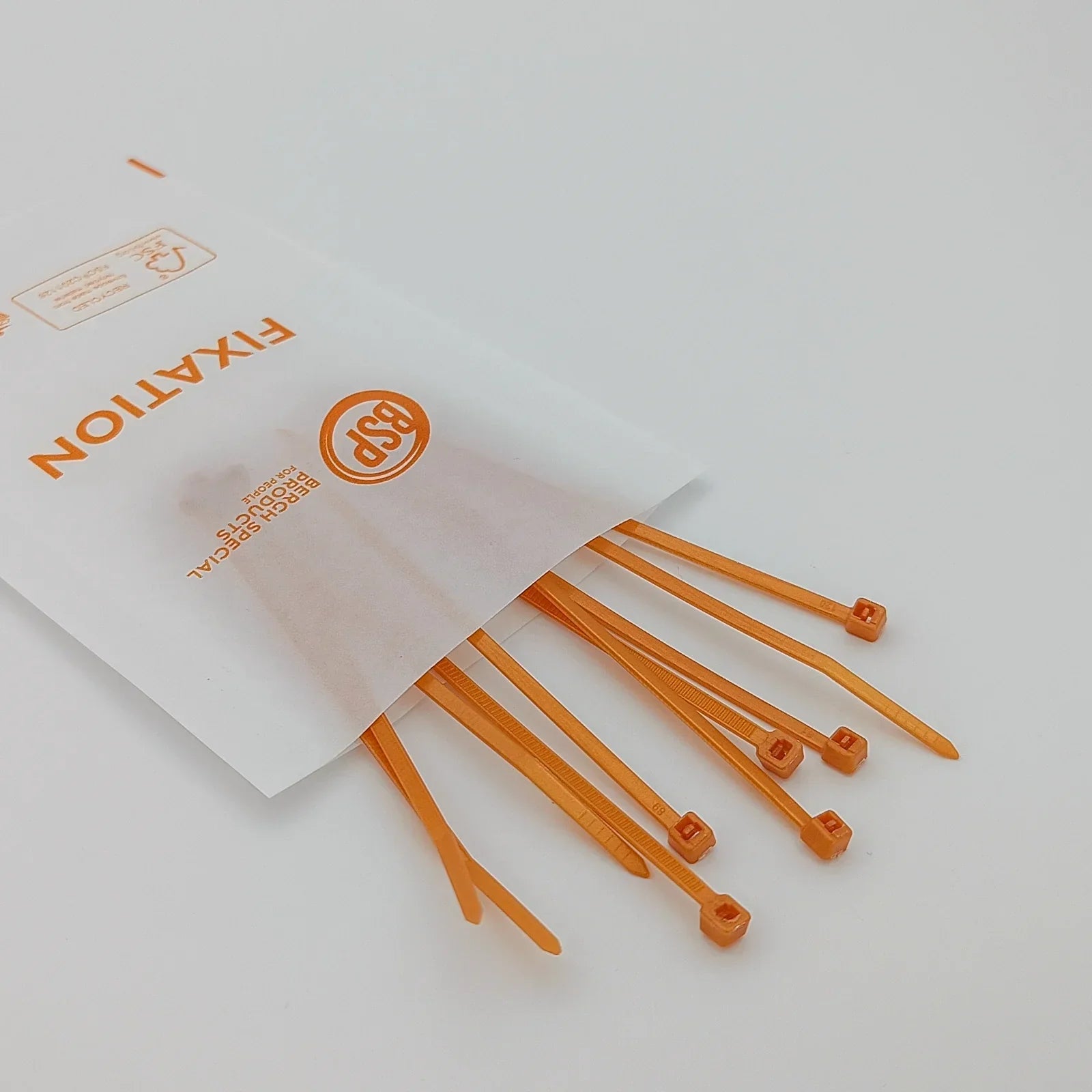 Orange plastic zip ties for wheelchair accessories, shown spilling from a 'FIXATION' labeled package