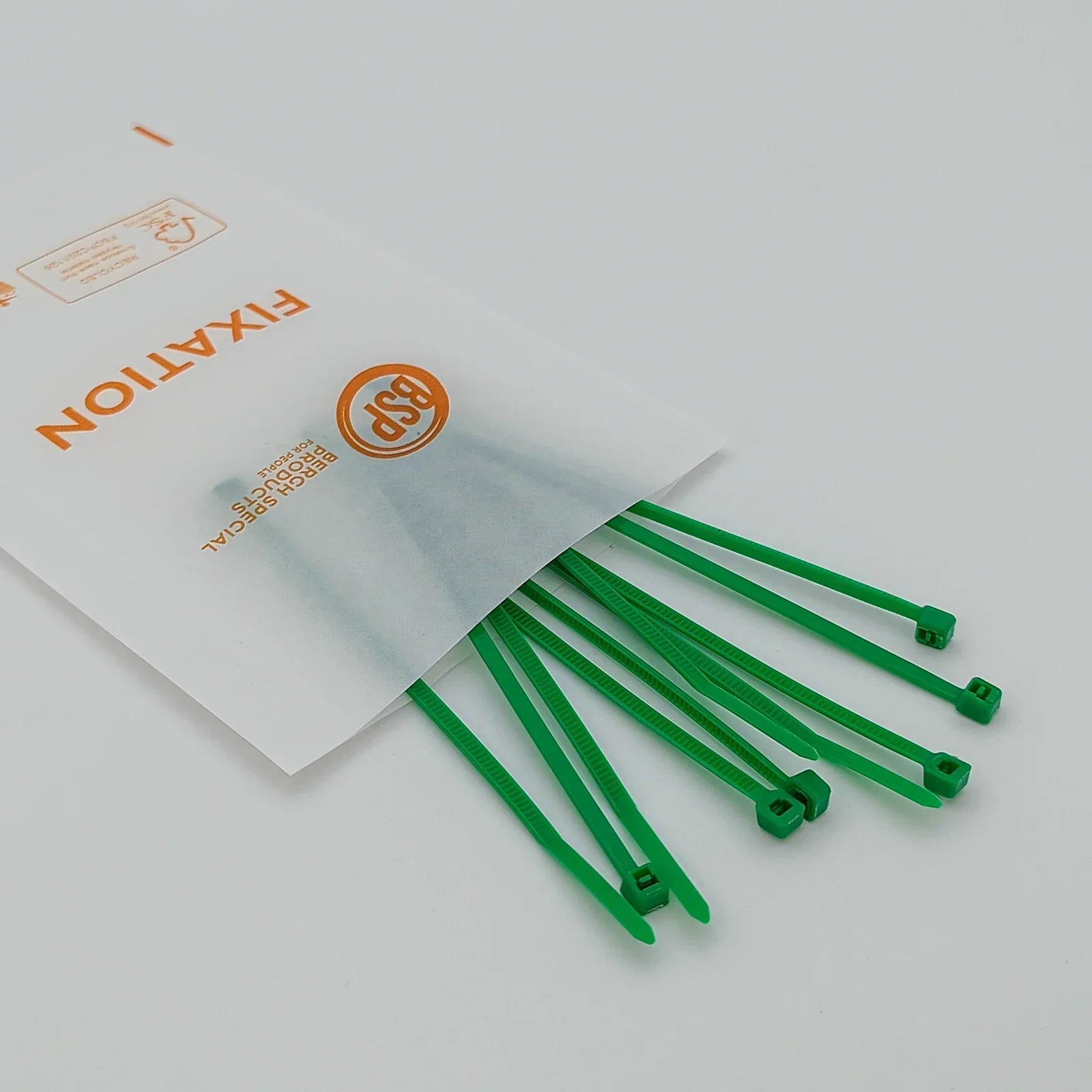 Green plastic cable ties for wheelchair accessories, packaged in a clear bag labeled 'FIXATION' for secure fastening.